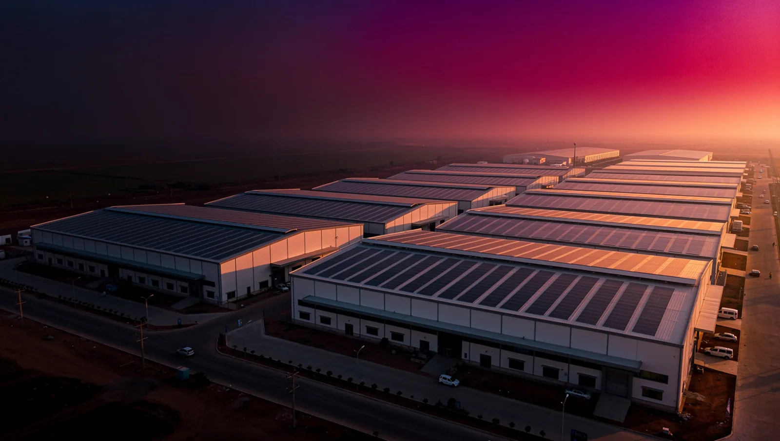 Aerial view of factory rooftops covered with solar panels at sunset in an industrial area of Gujarat